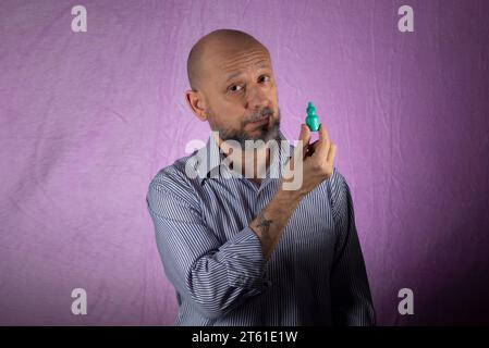 Mann, der grüne Arzneimittelverpackung vor rosa Hintergrund hält. Stockfoto
