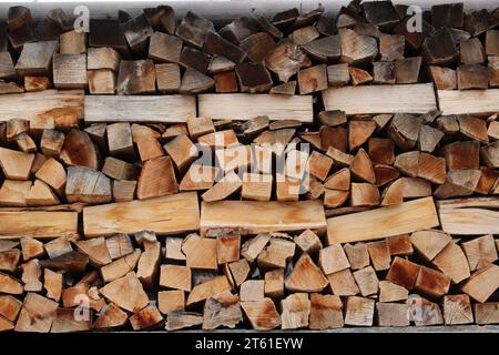 Kaminholzstapel im Freien mit mehr gereiften Holzstücken auf der Oberseite und frischeren auf der Unterseite. Verbrennung von Biokraftstoffen oder Biomasse. Vorbereitung auf das Winterkonzept Stockfoto