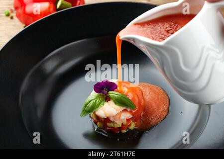 Kalte Gazpacho-Suppe mit Garnelen auf einem schwarzen Teller Stockfoto