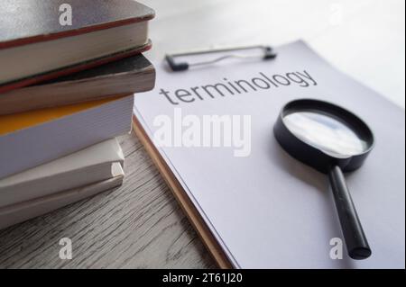 Nahaufnahme von Büchern, Lupe und Zwischenablage aus Papier mit TEXTTERMINOLOGIE. Stockfoto