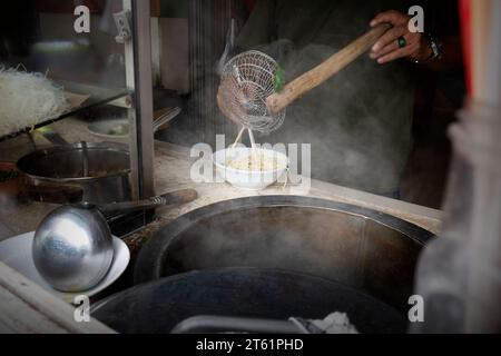Der Kellner bereitet Hähnchennudeln (Mie Ayam) zum Servieren zu. Traditionelles indonesisches Essen Stockfoto