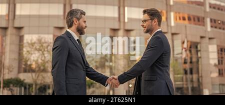Zwei Geschäftsmänner geben sich die Hand. Zwei Geschäftsleute kümmern sich um Handschlag im Freien. Stockfoto