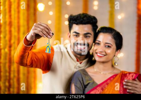 Konzentrieren Sie sich auf Schlüssel, glückliches, junges indisches Paar, das zu Hause neue Schlüssel zeigt - Konzept des Kaufs einer neuen Wohnung, Zweisamkeit und Investition. Stockfoto