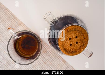 Schwarzer Tee in einer Glasschale und Glas-Teekanne auf einer Serviette von oben Stockfoto