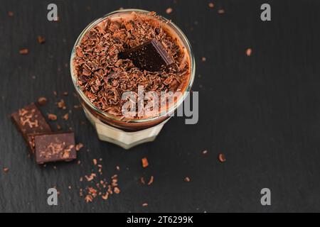 Vanillepudding mit Zartbitterschokolade. Perfektes köstliches Dessert aus nächster Nähe in einem Glas auf Servierbrett Stockfoto