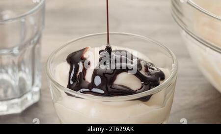 Mit Vanillepudding aus weißer Schokolade und dunkler Schokoladensauce. Nahaufnahme von Pudding in einem Glas Stockfoto