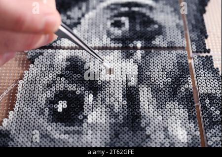 Pforzheim, Deutschland. November 2023. Oliver Lemke kreiert ein Hundeporträt aus aufbügelbaren Perlen in seiner Wohnung. Quelle: Uli Deck/dpa/Alamy Live News Stockfoto