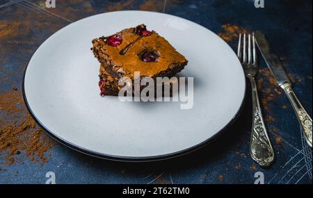 Leckerer Kirschbrownie, Brownies auf einem weißen Teller auf schwarzem Hintergrund, Nahaufnahme. Stockfoto