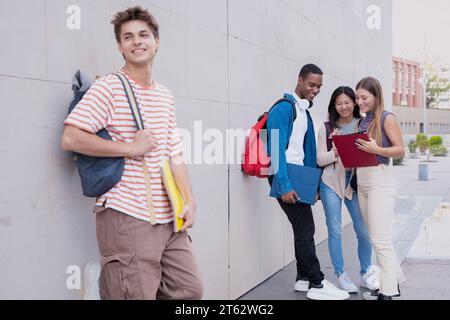 Glücklicher Student auf dem Campus, der draußen in die Kamera lächelt. Stockfoto