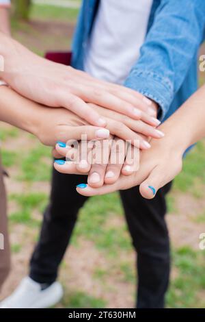 Nahaufnahme verschiedener junger Menschen, die draußen ihre Hände zusammenlegen. Stockfoto