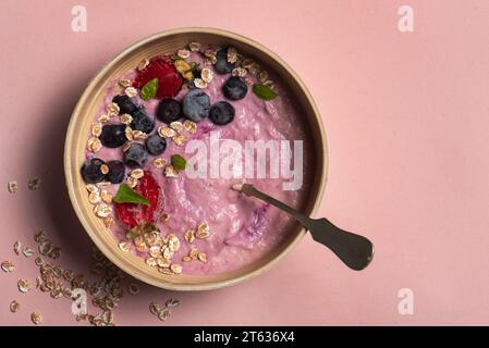 Erfrischendes Obst-Haferflocken mit Heidelbeeren, Erdbeeren und Haferflocken auf hellrosa Hintergrund. Nahaufnahme, Draufsicht Stockfoto