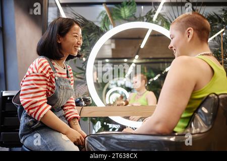 Seitenansicht Porträt eines lächelnden jungen Friseurberaters in modernem Schönheitssalon Stockfoto