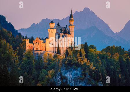 Schloss Neuschwanstein, beleuchtet nach Sonnenuntergang, umgeben von Herbstfarben, in der Nähe der Stadt Füssen, im Allgäu, in Bayern, Süden Stockfoto