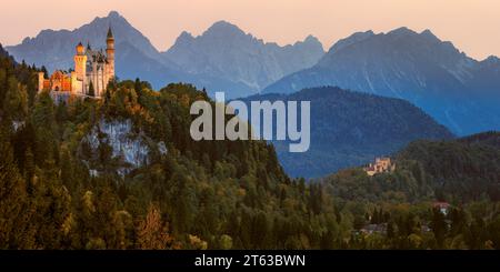 Ein breites 2:1-Panoramabild von Schloss Neuschwanstein, beleuchtet nach Sonnenuntergang, umgeben von Herbstfarben, in der Nähe der Stadt Füssen, in Th Stockfoto