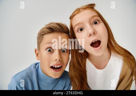 Nahaufnahme von fröhlich verwunderten Freunden in warmen Outfits, die direkt in die Kamera schauen, Modekonzept Stockfoto