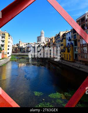 Girona, mit der Struktur der Pont de les Peixateries Velles über dem Onyar River mit Gironas strenger Kathedrale, die über die bunten Dächer hinausragt Stockfoto