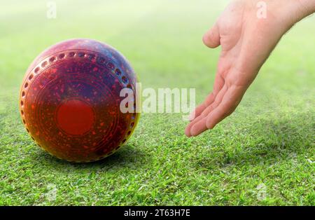 Eine männliche Hand Bowling und eine rote Rasen Bowlingkugel auf einer grünen Rasenfläche freigeben - 3D-Rendering Stockfoto