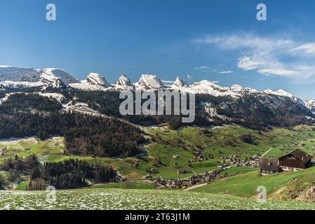 Blick auf die schneebedeckten Churfirsten und das Dorf Alt St. Johann, Toggenburg, Wildhaus-Alt St. Johann, Kanton St. Gallen, Schweiz Stockfoto