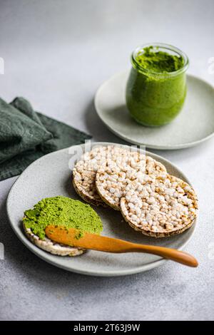 Hoher Winkel von Reisbrot auf einem Teller, begleitet von einer lebhaften grünen Spinat-Pesto-Pasta-Sauce in einem Glas, vor einer verschwommenen Kulisse in der Nähe von Napki Stockfoto