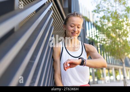 Foto von Metropolitan Run: Aktive Frau überprüft die Zeit vor dem Training Stockfoto