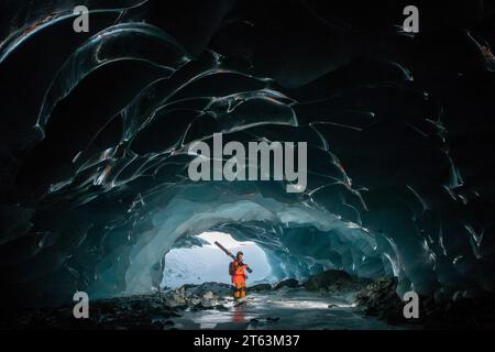 Seitlicher Blick auf Skifahrer mit Skistöcken, die in einer Höhle auf verschneiten Bergen spazieren gehen, während Sie während des Urlaubs in den Schweizer Alpen erkunden Stockfoto