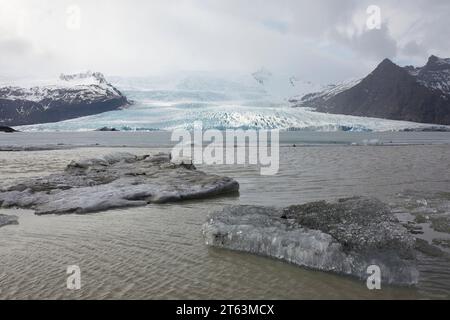 Malerischer Blick auf Gletscher und gefrorenen See mit schneebedeckten Bergen gegen Himmel im Winter auf Island Stockfoto