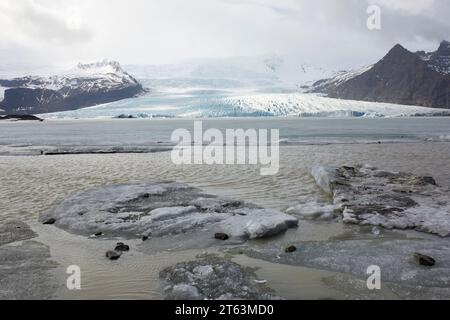 Malerischer Blick auf Gletscher und gefrorenen See mit schneebedeckten Bergen gegen Himmel im Winter auf Island Stockfoto