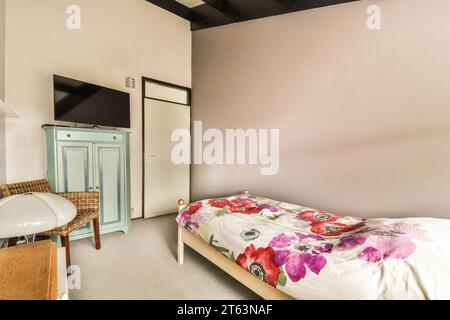 Kleines komfortables Bett mit Fernseher im Kleiderschrank im geräumigen Schlafzimmer mit weißen Wänden in einem modernen Apartment Stockfoto