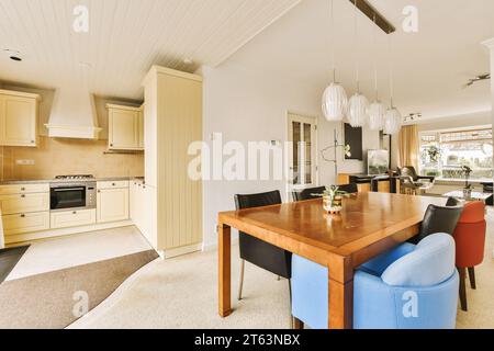 Holztisch und Stühle im Esszimmer eines modernen Hauses mit Küche und Wohnzimmer im Hintergrund Stockfoto