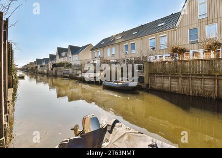 Kleine Boote, die an einem ruhigen Kanal vor Häusern in einer Reihe unter blauem Himmel in der Stadt an sonnigen Tagen vor Anker liegen Stockfoto