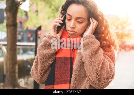 Das Außenporträt einer aufgewühlten jungen Frau in einer Jeansjacke spricht am Telefon über das Lifestyle-Foto Stockfoto