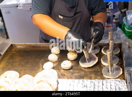 Küchenchef Presse Metallteller Braten Hotteok, koreanische süße Straßenpfannkuchen, traditionelles Essen in Korea Stockfoto