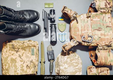 Ukrainische Militärausrüstung flach gelegt Hintergrund. Militärkleidung, Zubehör, Wärmebildkamera, Munition, Kampfstiefel, Messer mit Nationa Stockfoto