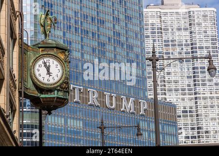 Die Uhr im Juweliergebäude wird kurz vor Hochmittags angezeigt. Im Hintergrund sehen Sie die Schrift Trump aus dem Trump Tower. Chicago, Usa Stockfoto