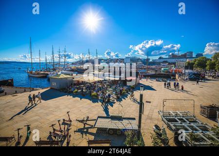 Oslo, Norwegen, 27. August 2022: Malerische Uferpromenade von Oslo im Sommer. Viele Leute laufen an einem hellen Sommertag zu Fuß an einem beliebten Touristenort. Kopf Stockfoto