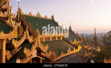 Yangon, Myanmar. Der Sonnenaufgang über der Shwedagon-Pagode feuert das Pyatthat (gestuftes Dach) auf, während Yangon im Hintergrund im Nebel verloren ist Stockfoto
