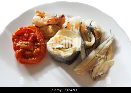Teller mit Hor d'oeuvres einschließlich Brötchenhering, verschiedenen Meeresfrüchten, sonnengetrockneten Tomaten und Sardellen - John Gollop Stockfoto