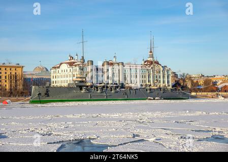 ST. PETERSBURG, RUSSLAND - 12. FEBRUAR 2022: Der Kreuzer Aurora vor dem Hintergrund der Nakhimow-Schule an einem Wintertag. Sankt Petersburg Stockfoto