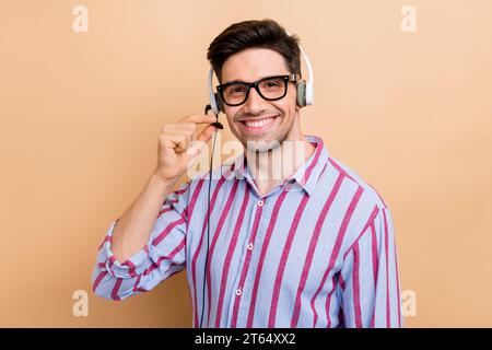 Junge lächelnde Kundenbetreuung Support Operator Mann Foto des professionellen Anrufer berühren Mikrofon isoliert auf beigefarbenem Hintergrund Stockfoto
