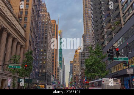 Blick auf die 36th Street in Manhattan mit Wolkenkratzern und geschäftigem Transport, vor dem Hintergrund des blauen Himmels mit weißen Wolken. New York. USA. Stockfoto