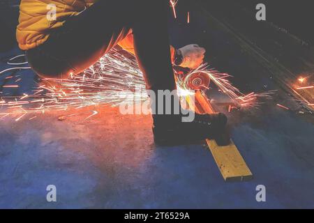 Arbeiten mit einem Winkelschleifer. Verstoß gegen Sicherheitsvorschriften Stockfoto