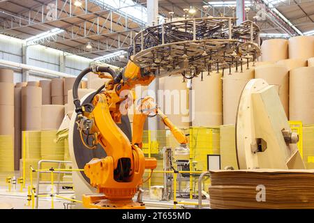 Ein Roboterarm, der große Papierrollen in einer Papierfabrik verpackt. Stockfoto