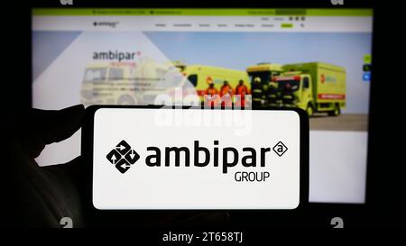 Person, die ein Mobiltelefon mit dem Logo des brasilianischen Umweltdienstleisters Ambipar Group vor der Webseite hält. Schwerpunkt auf dem Display des Telefons. Stockfoto