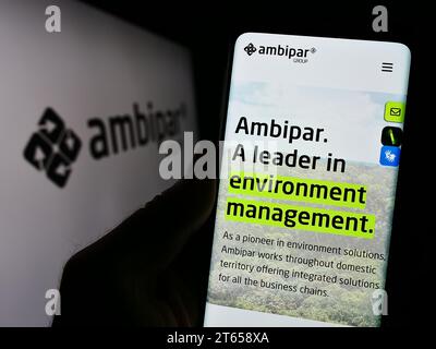 Person mit Mobiltelefon mit Webseite des brasilianischen Umweltdienstleisters Ambipar Group mit Logo. Konzentrieren Sie sich auf die Mitte des Telefondisplays. Stockfoto