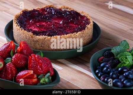 Süßer Kuchen, der mit roten Früchten bedeckt ist, noch nicht fertig. Stockfoto