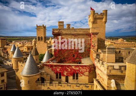 Blick auf die Burg und den Palast der Olite in Navarra, Spanien, mit seinen schlanken Türmen und der roten Weinrebe, die an den Mauern hinaufsteigt Stockfoto