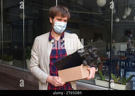 Ein männlicher Geschäftsmann mit Schutzmaske wurde wegen der Coronavirus-Krise aus seinem Job entlassen. Wirtschaftskrise, Depression, Arbeitslosigkeit Stockfoto