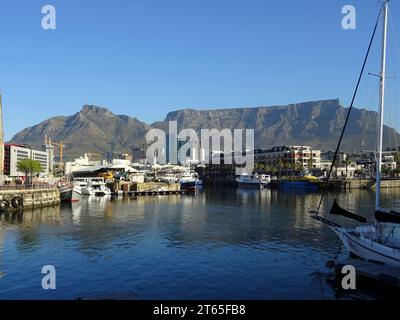 Boote und Yachten, die im Hafen von Victoria and Alfred Waterfront festgemacht sind, mit dem Tafelberg, der über der Stadtsilhouette von Kapstadt aufragt Stockfoto