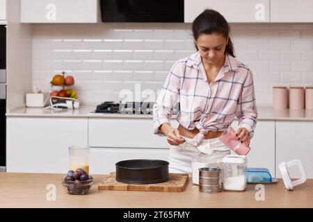 Hübsche Frau, die Teig für Kuchen in der modernen Küche zubereitet Stockfoto