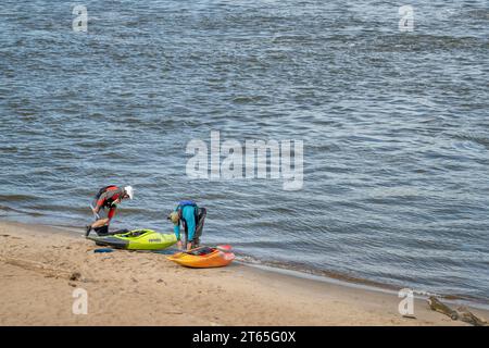 Granite City, Il, USA – 8. Oktober 2023: Zwei Kajakfahrer starten Wildwasserkajaks von einem Strand am Mississippi River unterhalb eines Wassers des Low W Stockfoto